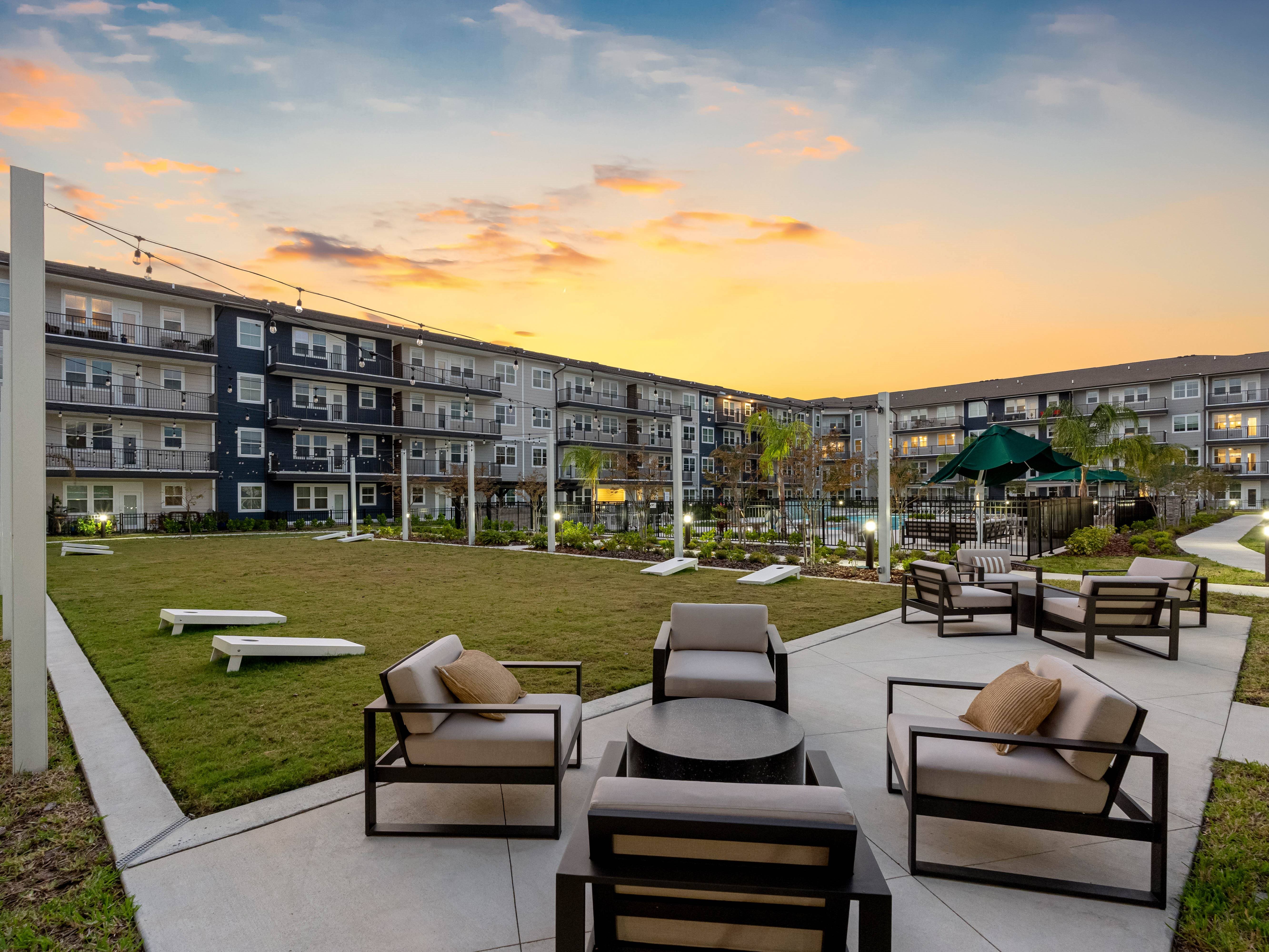 A sunset view of a patio with chairs and tables.